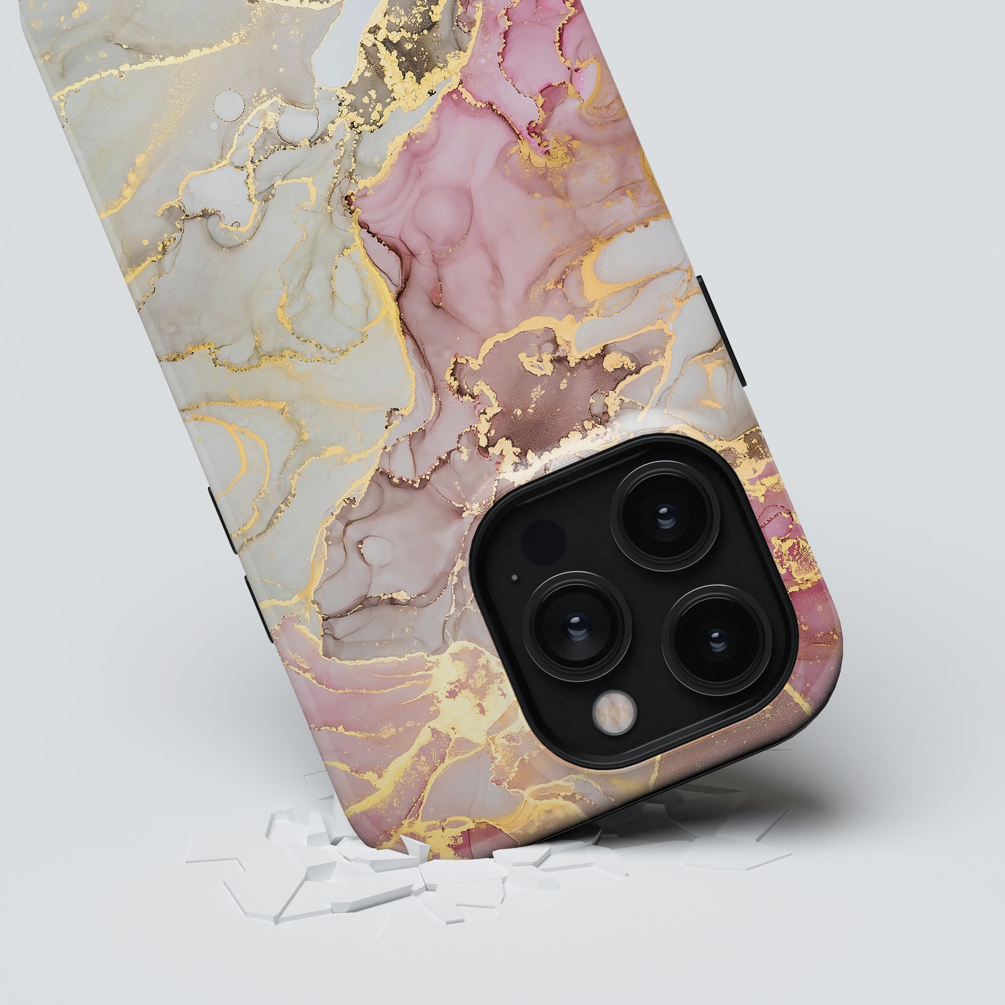 A smartphone adorned with the Glitter - Tough Case, featuring a marble-patterned design in gold, pink, and cream colors, rests on a light surface with subtle white cracks. This case exudes timeless elegance while offering robust protection for your device.