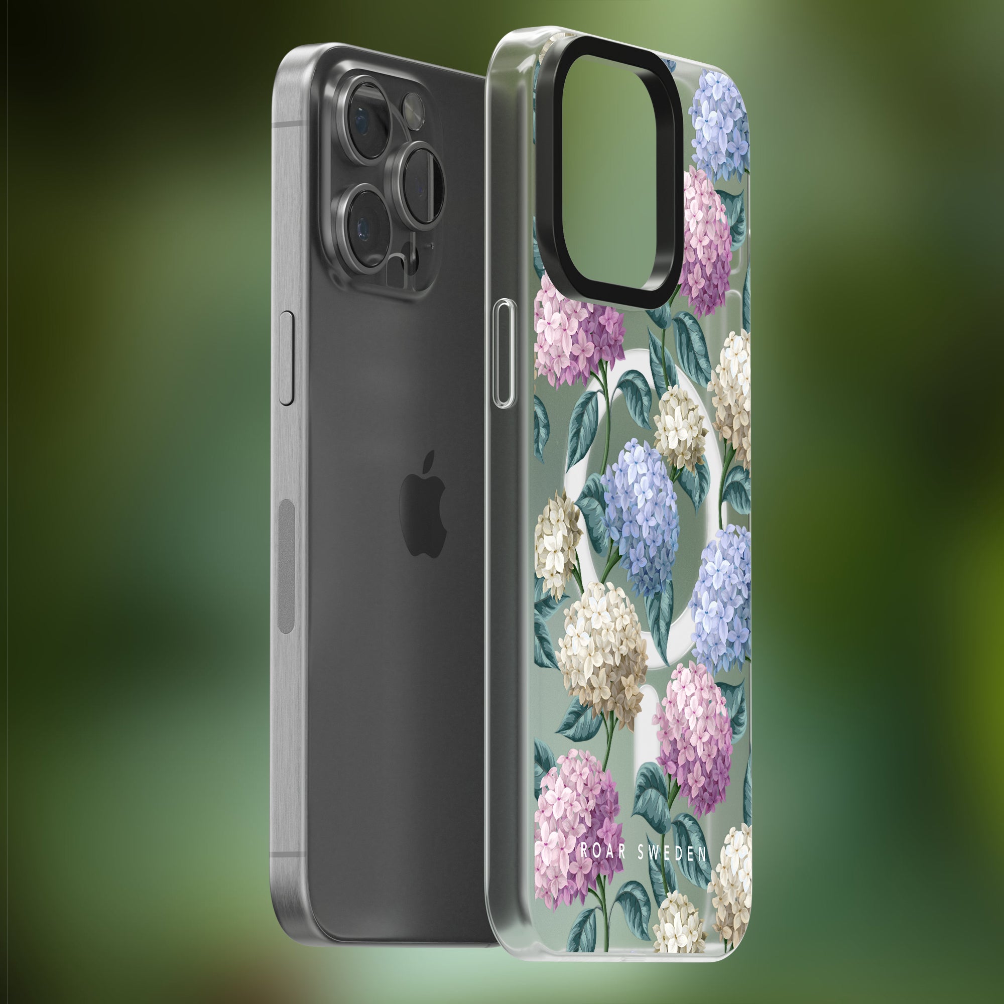Two smartphones, one in a clear Hydrangea - MagSafe Case with hortensiablommans designs and the other without a case, are displayed against a blurred green background.