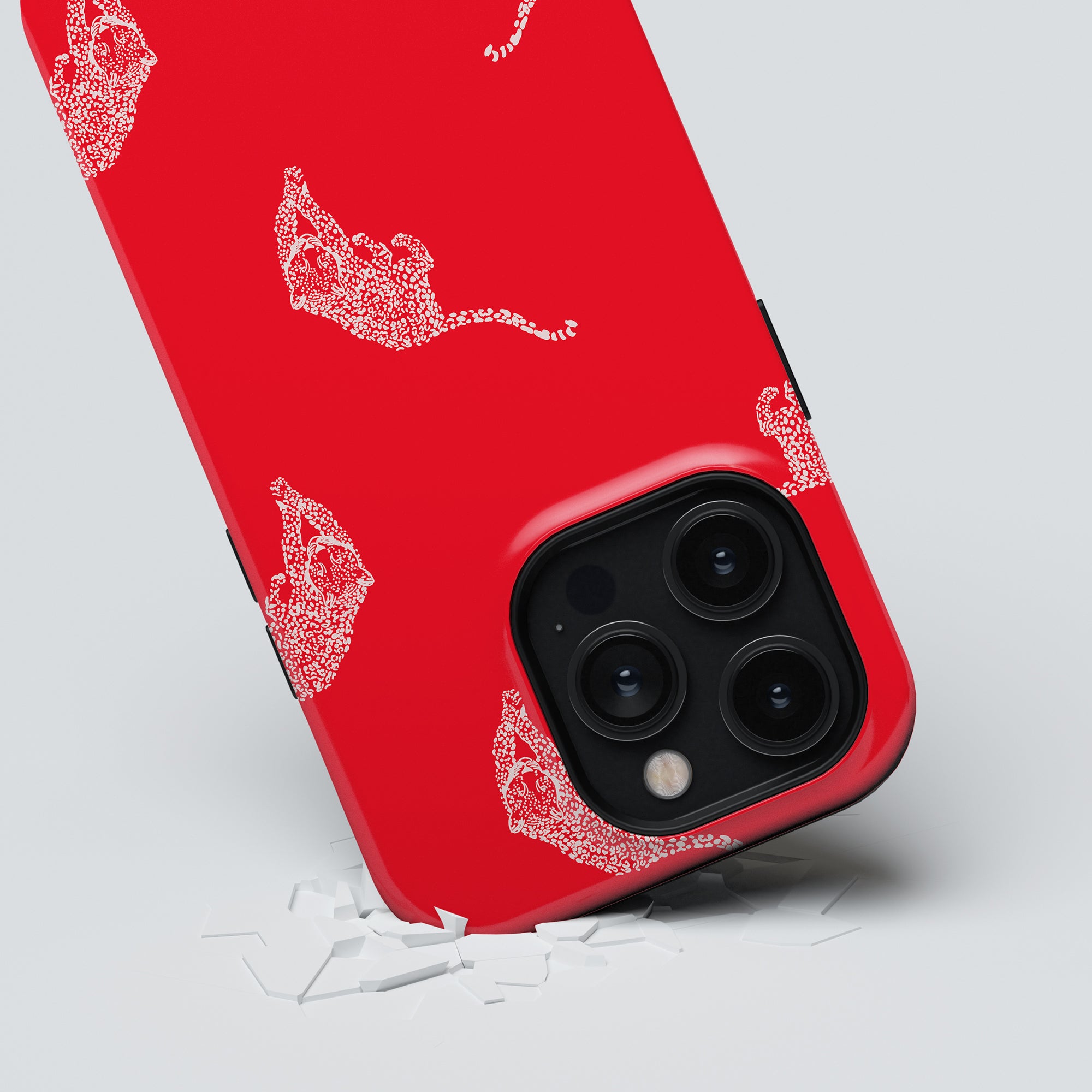 The Kitty Red Tough Case, featuring an elegant white animal design on a red background, is pictured with its corners resting on broken white shards, showcasing the phone's camera lenses and blending style and protection seamlessly.