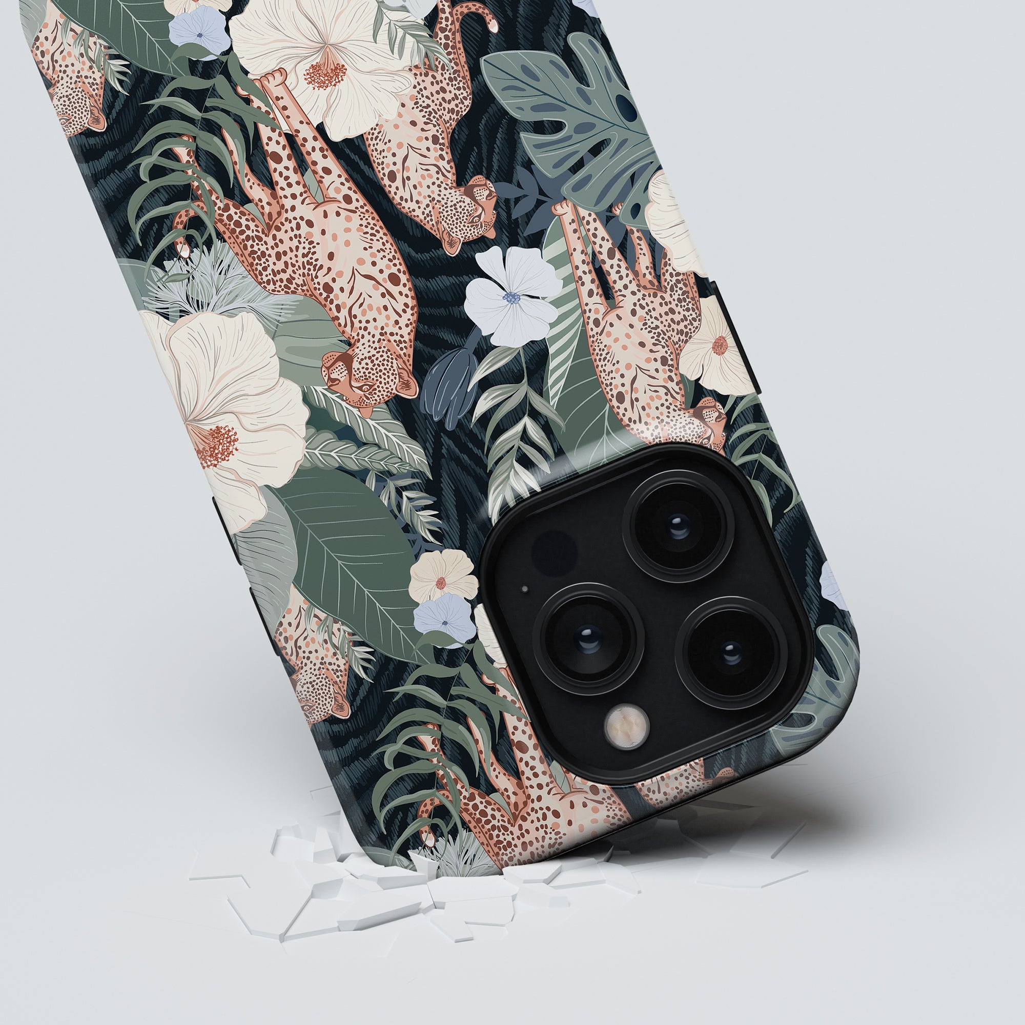 A smartphone with a Leopardess - Tough Case lying face down, its camera lenses visible against a broken glass background.