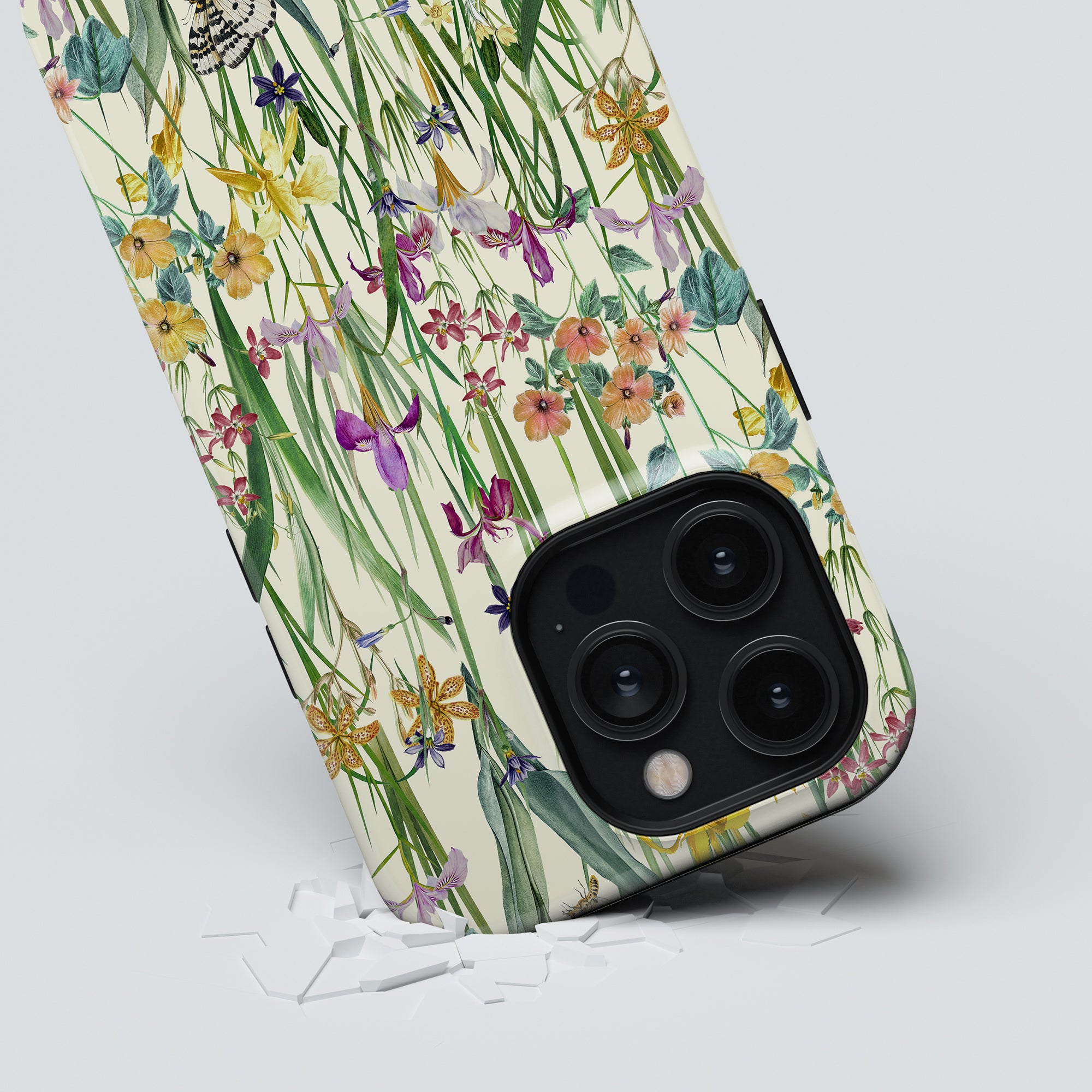 A smartphone with a Blooming Meadow - Tough Case showing a shattered screen area near the camera lenses, now wrapped in breathable material for added protection.
