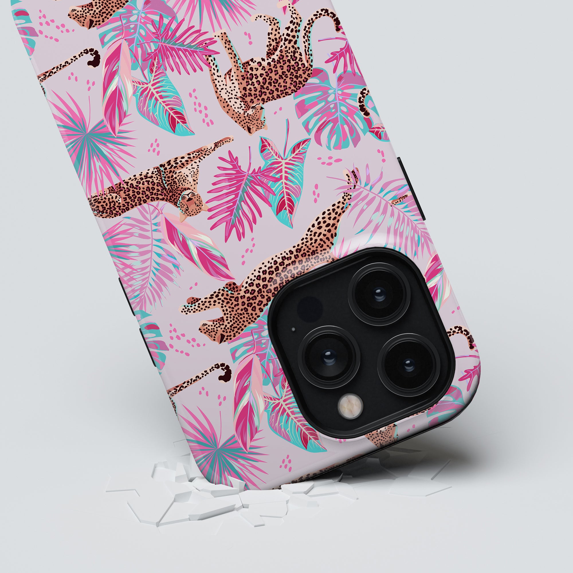 A Chill Tough Case with a tropical pink and leopard print design, partially breaking through a white surface.