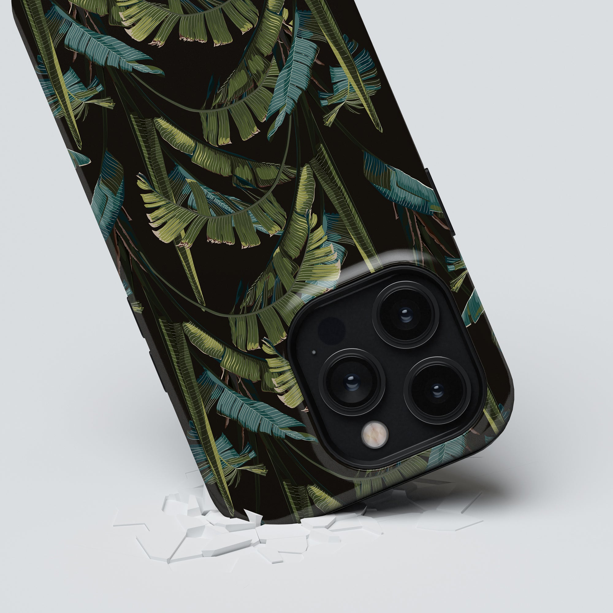 Smartphone with a Mystic Jungle - Tough Case showcasing a tropical leaf pattern making an impression on a white surface.
