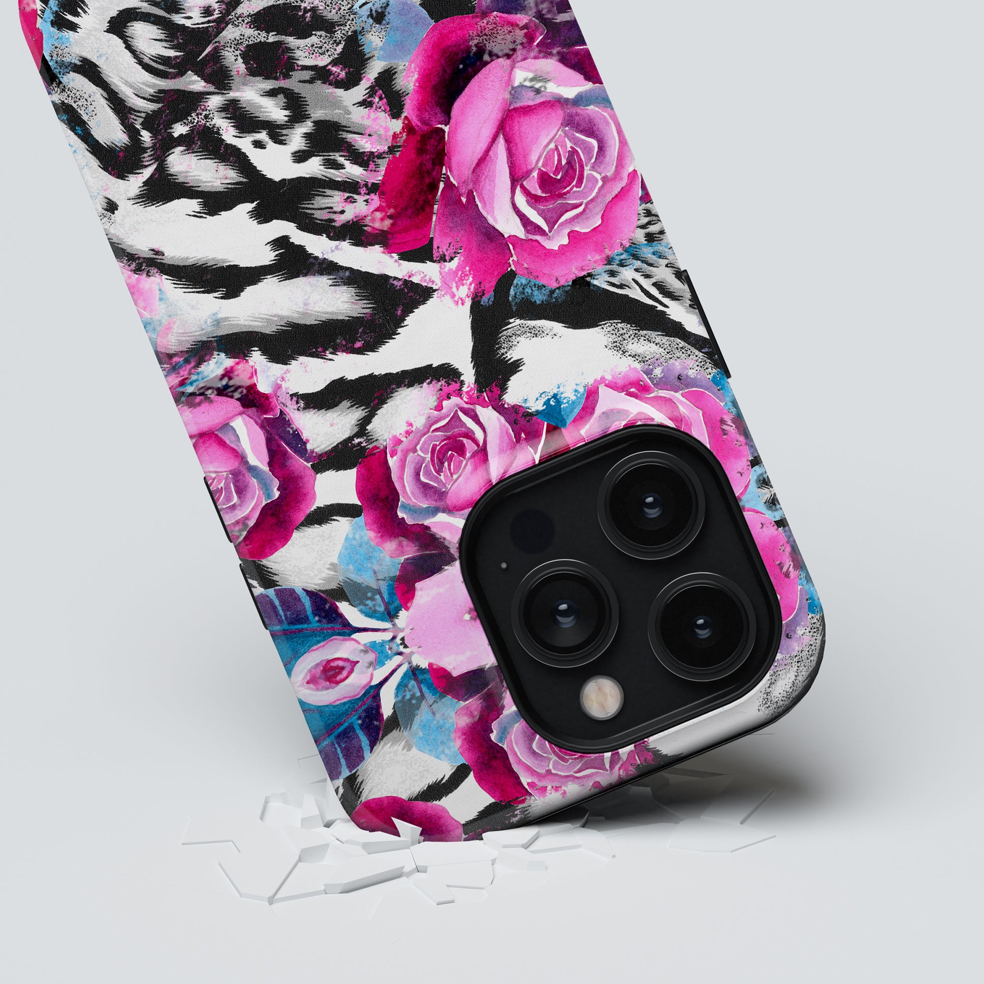 Smartphone with a Rosy Wildcat - Tough Case, featuring a large camera lens, lying on a white surface with broken glass fragments.