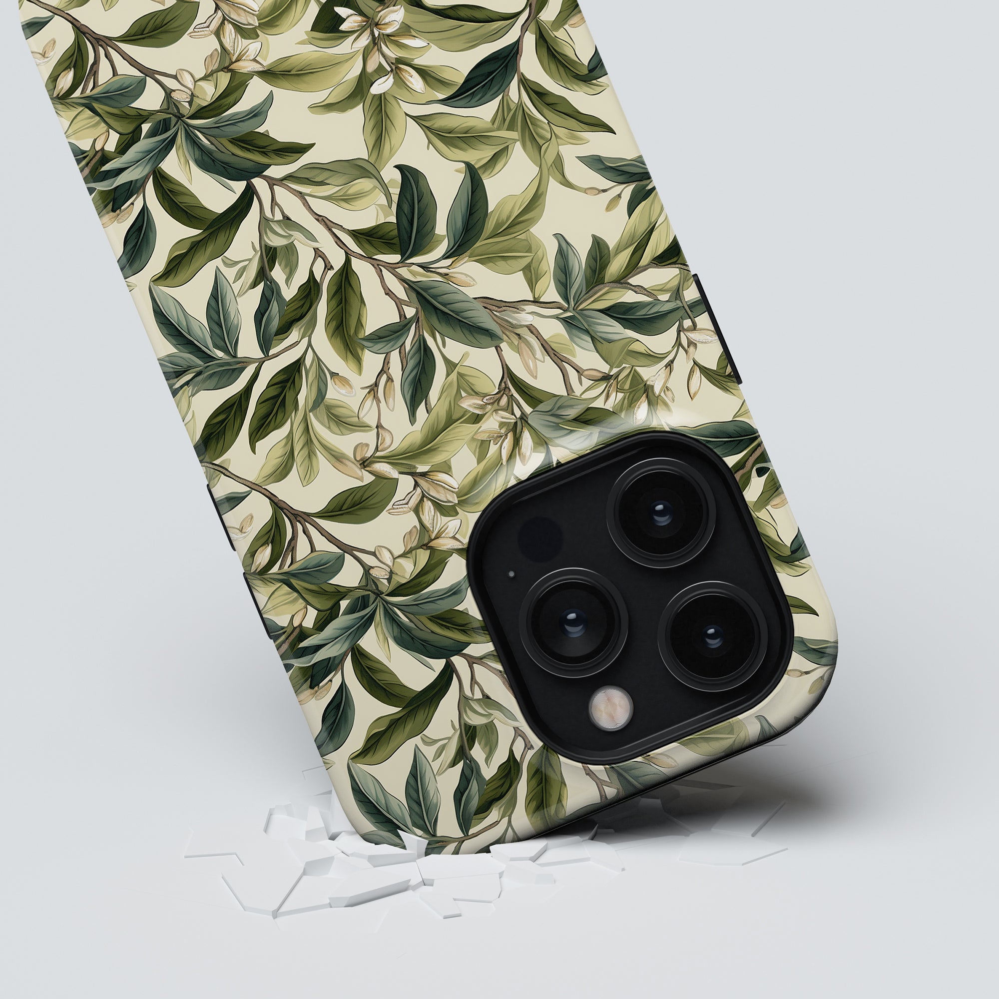 The Tea Leaves - Tough case from the Floral Collection is shown leaning on its corner, with small shards of a broken screen protector scattered below it.